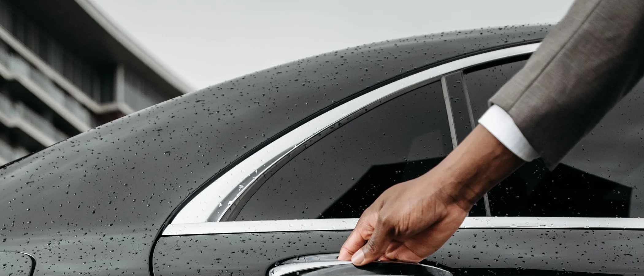 A chauffeur opening the door of a black luxury sedan